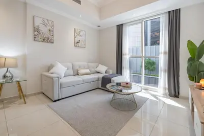 a living room with a couch and a table at Dunya Tower Downtown 1BR Balcony Pool View 2Min to Dubai Mall in Dubai