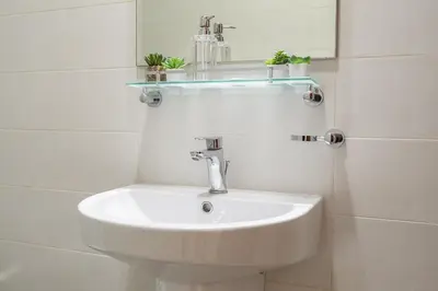 a white bathroom with a sink and a mirror at Dunya Tower Downtown 1BR Balcony Pool View 2Min to Dubai Mall in Dubai