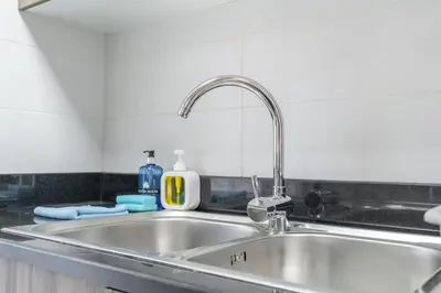 a kitchen sink with a faucet on top of it at Dunya Tower Downtown 1BR Balcony Pool View 2Min to Dubai Mall in Dubai