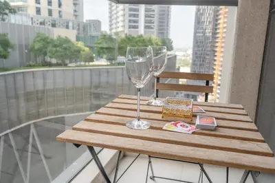 a wooden table with two wine glasses on a balcony at Dunya Tower Downtown 1BR Balcony Pool View 2Min to Dubai Mall in Dubai
