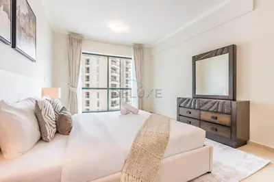 a bedroom with a white bed and a dresser and a mirror at Spacious 1BR Overlooking City Skyline and Marina, Next to JLT Lakefront, Just Minutes to Metro, Jumairah Bay Tower X1, JLT by Deluxe Holiday Homes in Dubai