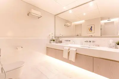a white bathroom with two sinks and a toilet at Scenic Studio at Palm Tower in Dubai