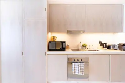 a kitchen with white cabinets and a microwave at Scenic Studio at Palm Tower in Dubai