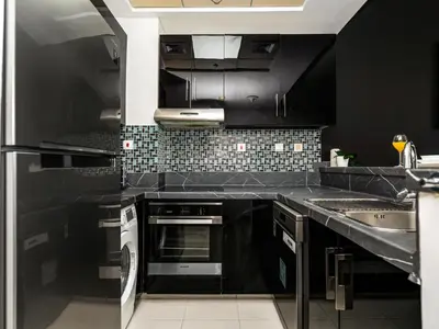 a kitchen with black cabinets and a sink at Bright & Stylish Studio with Marina Views in Dubai