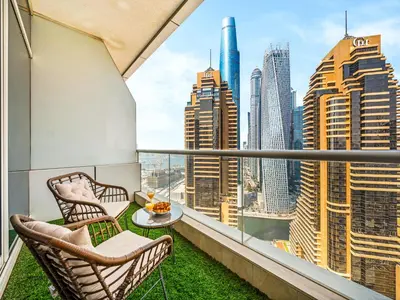 a balcony with two chairs and a view of the city at Bright & Stylish Studio with Marina Views in Dubai