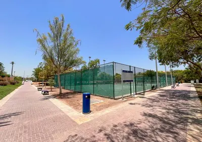 a chain link fence with a tennis court at Lux JVT Resort Pools Spa Gym Kids Play in Dubai