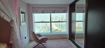 a bedroom with a chair and a large window at Homeeza Luxury 2BR Apartment Sea Views Dubai Marina in Dubai