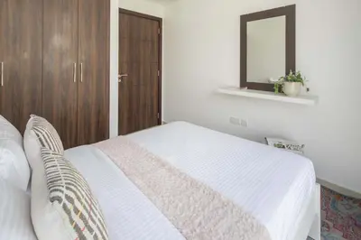 a bedroom with a white bed and a mirror at Frank Porter - Avencia, Damac Hills 2 in Dubai