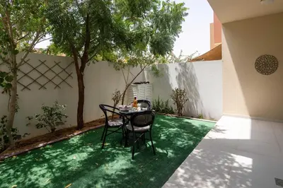 a patio with a table and chairs on a green lawn at Frank Porter - Avencia, Damac Hills 2 in Dubai
