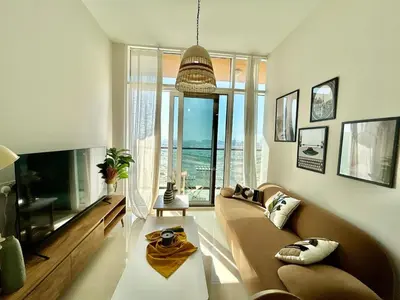 a living room with a couch and a large window at Homes2Retreat - Golf & Desert Views - Luxe 1BR Escape in Dubai