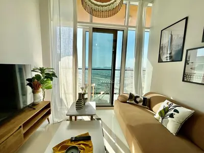 a living room with a couch and a large window at Homes2Retreat - Golf & Desert Views - Luxe 1BR Escape in Dubai