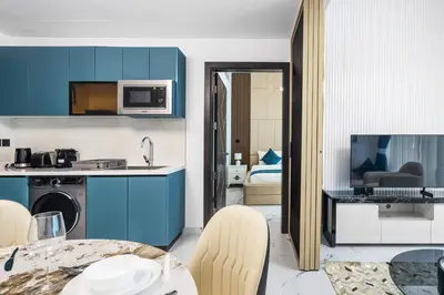 a kitchen with blue cabinets and a table with chairs at ALiving Modern 1BR I Private Pool I Opalz by Danube- 1704 in Dubai