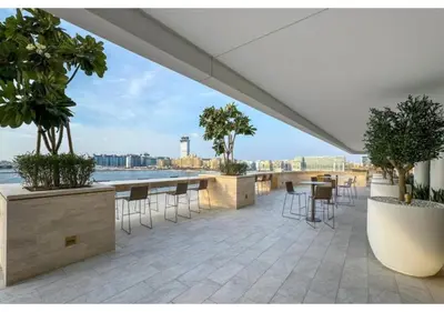 a patio with tables and chairs and a view of the water at KeyRock - Sea View Stay with Pool Access in Dubai