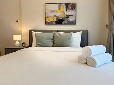 a bedroom with a white bed with towels on it at ASHRI HH Condo In Riviera Meydan in Dubai