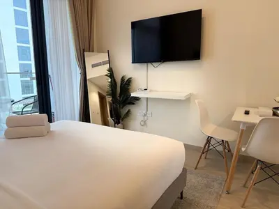 a hotel room with a bed and a television on the wall at ASHRI HH Condo In Riviera Meydan in Dubai