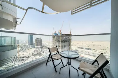 a table and chairs in a room with a large window at Modern and Spacious Studio Al Barsha South Stay in Dubai