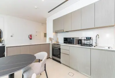 a kitchen with white cabinets and a table and chairs at Luxe 1 Bedroom with High Floor close to Dubai Mall in Dubai