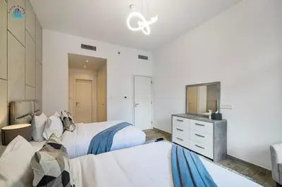 a bedroom with two beds and a dresser and a mirror at Furnished 2BR with Vibrant View in Dubai