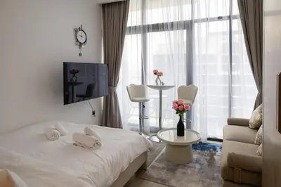 a bedroom with a bed and a tv and a couch at Luxe Studio Vibes Stylish & All New Pet Free in Dubai