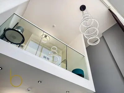 a staircase with glass railing and a chandelier at Bookable -1 Bed Rukan Townhouse with Clubhouse Access in Dubai