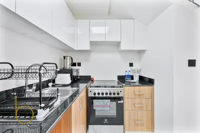 a kitchen with white cabinets and a stove top oven at Bookable -1 Bed Rukan Townhouse with Clubhouse Access in Dubai