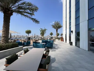 a patio with tables and chairs and a palm tree at Iconic 3BHK I Stunning Creek Views I Sleep up to 6 guests I High Floor I Pool I Free Parking I Pet Friendly I in Dubai