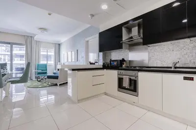 a kitchen with white appliances and a living room at TRPS - Maison Mall Street, Downtown - Close to Dubai Mall, Fully Furnished 1BR in Dubai
