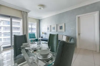a dining room with a glass table and green chairs at TRPS - Maison Mall Street, Downtown - Close to Dubai Mall, Fully Furnished 1BR in Dubai