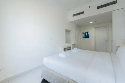 a white bedroom with a white bed and a window at TRPS - Maison Mall Street, Downtown - Beautifully Appointed 1BR, Near to Burj Khalifa in Dubai