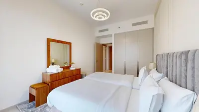a white bedroom with a bed and a mirror at Exclusive Burj Khalifa View Luxury 2BR Next to Dubai Mall - Like Home in Dubai