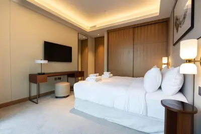 a hotel room with a white bed and a television at TRPS - Address Opera, Downtown - Burj Khalifa View, Luxury 3BR Living in Dubai