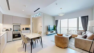 a kitchen and living room with a table and a couch at Panaromic Burj Khalifa View from Balcony - Luxury 2BR next to Dubai Mall - Like Homes in Dubai