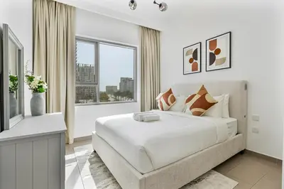 a white bedroom with a bed and a window at Radiant 2BR APT near Dubai Hills Park & Golf Club in Dubai