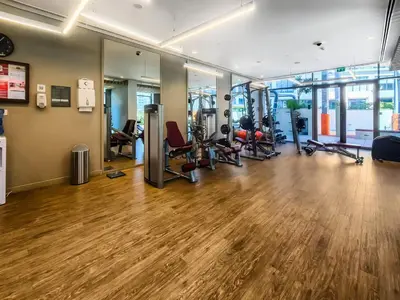 a gym with treadmills and exercise equipment on a wooden floor at Radiant 2BR APT near Dubai Hills Park & Golf Club in Dubai