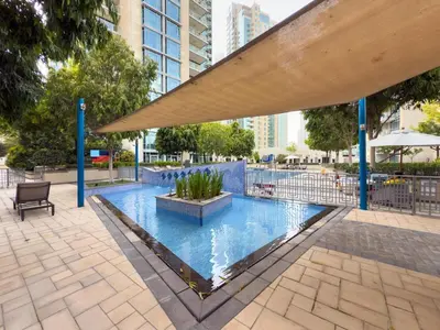 a large swimming pool with a bench and an umbrella at GuestReady - Downtown View | 1BR + Sofa Bed in Dubai