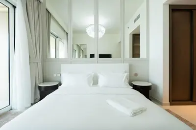 a white bedroom with a large white bed with mirrors at KeyRock - Palm View Luxury Stay in Grand Bleu in Dubai