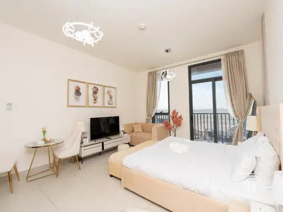 a white bedroom with a large bed and a living room at Brand New High Floor Studio in Midtown Dubai in Dubai
