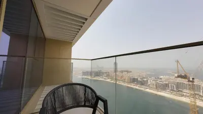 a balcony with a chair and a view of the city at Elegant Seaside Luxury 1BR in Beachfront, Grand BLeu Tower, Pool & Gym in Dubai