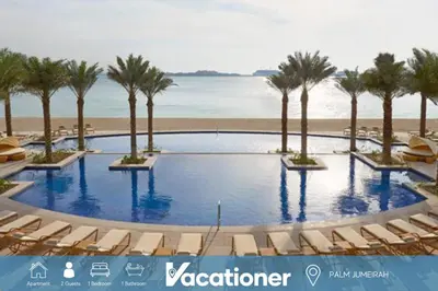 a pool with chairs and palm trees on the beach at Al Dabas 2 - Calm One Bedroom in Palm Jumeirah in Dubai