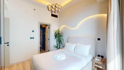 a bedroom with a white bed with a chandelier at Ocean Heights - Upgraded Two Bed with Sea View in Dubai
