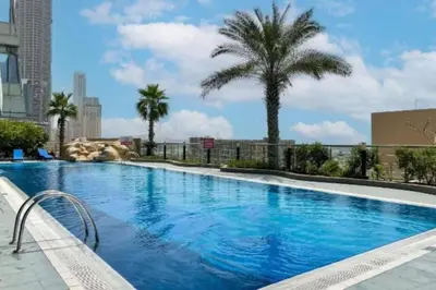 a large swimming pool with a palm tree in a city at Ocean Heights - Upgraded Two Bed with Sea View in Dubai