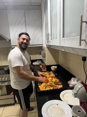 a man standing in a kitchen preparing food at Happyland JBR Dubai Hostel in Dubai