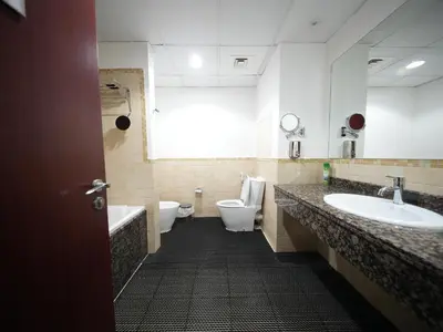 a bathroom with two toilets and a sink and a tub at Happyland JBR Dubai Hostel in Dubai