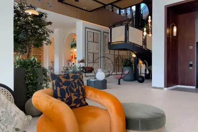 an orange chair in a lobby with a staircase at Dubai Hills Cozy 1Br Golfville in Dubai