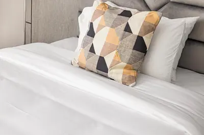 a white bed with a pillow on top of it at Contemporary 2-BR at Belgravia Square JVC in Dubai