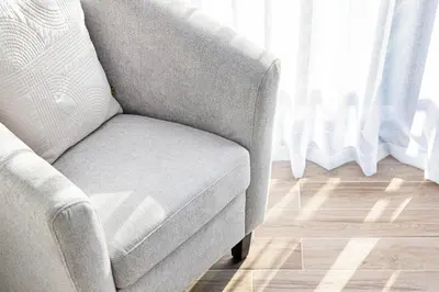 a gray chair in a room with a wooden floor at Contemporary 2-BR at Belgravia Square JVC in Dubai