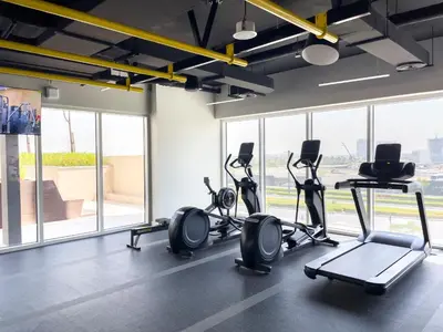 a gym with treadmills and ellipticals in a room with windows at Chic & Modern 1BR in Socio Near Dubai Hills Park in Dubai