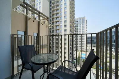 a balcony with a table and chairs and a view of buildings at Chic & Modern 1BR in Socio Near Dubai Hills Park in Dubai