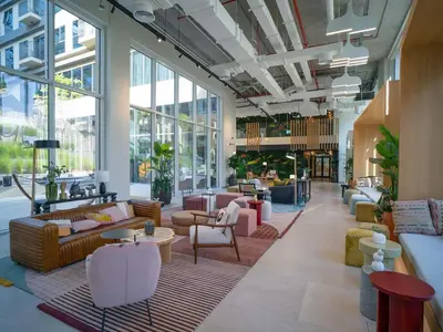 a large lobby with couches and tables and windows at Chic & Modern 1BR in Socio Near Dubai Hills Park in Dubai
