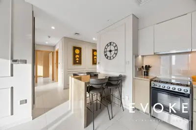 a kitchen with white cabinets and a counter with stools at Full Burj & Fountain View - Evoke 2BR at Burj Royale in Dubai